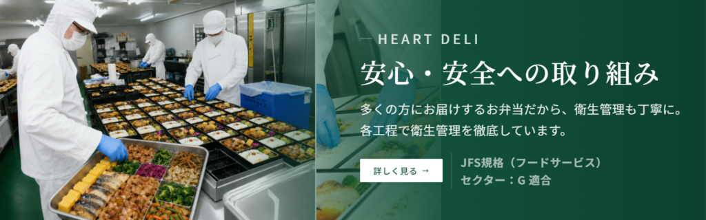 お弁当の盛り付けを行うアポルテフードファクトリーの厨房と、ハートデリの安心・安全への取り組みを案内するバナー
